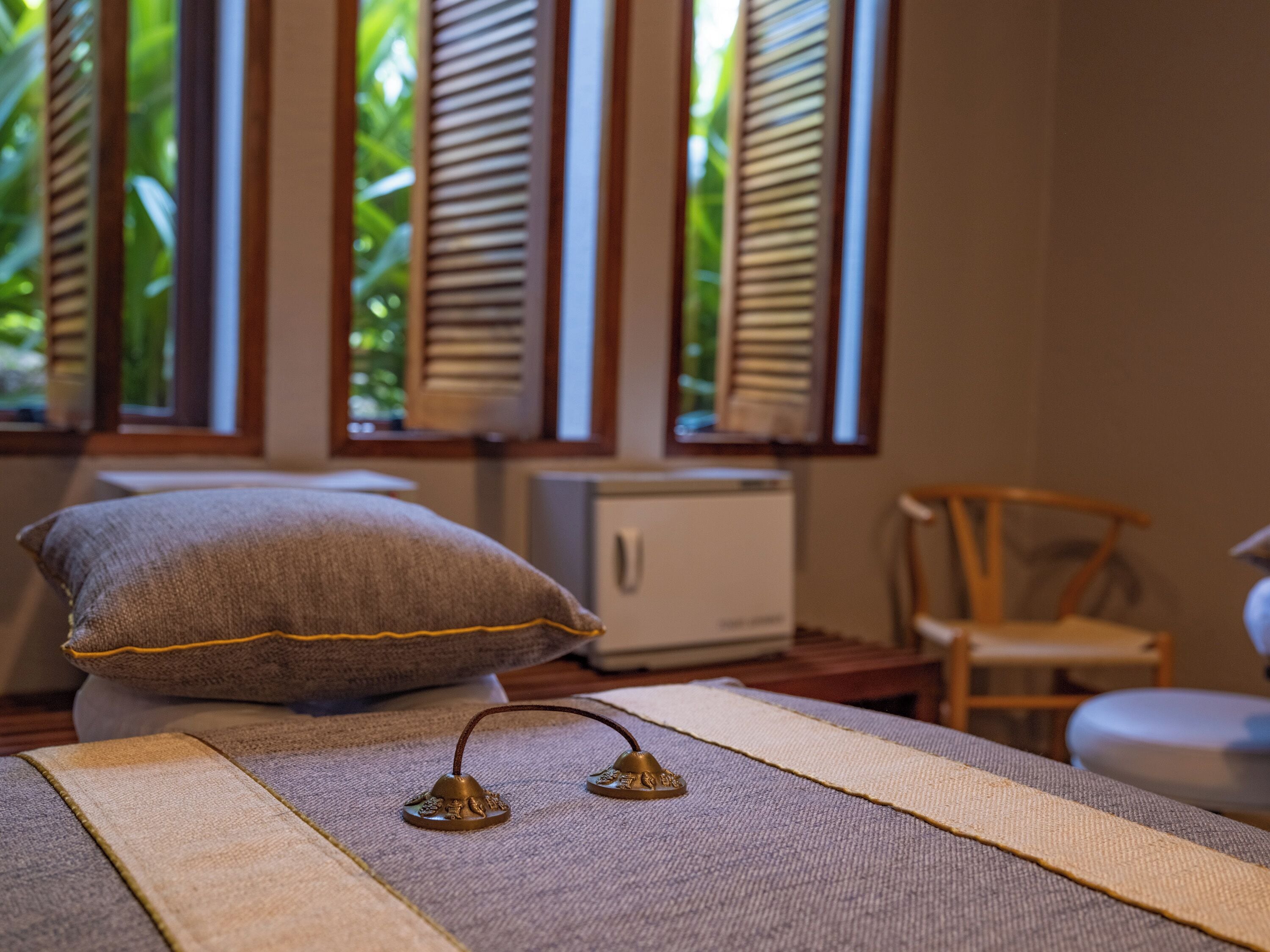 Ein Zimmer mit Bett, Kissen, einem kleinen Tisch und einem Stuhl.