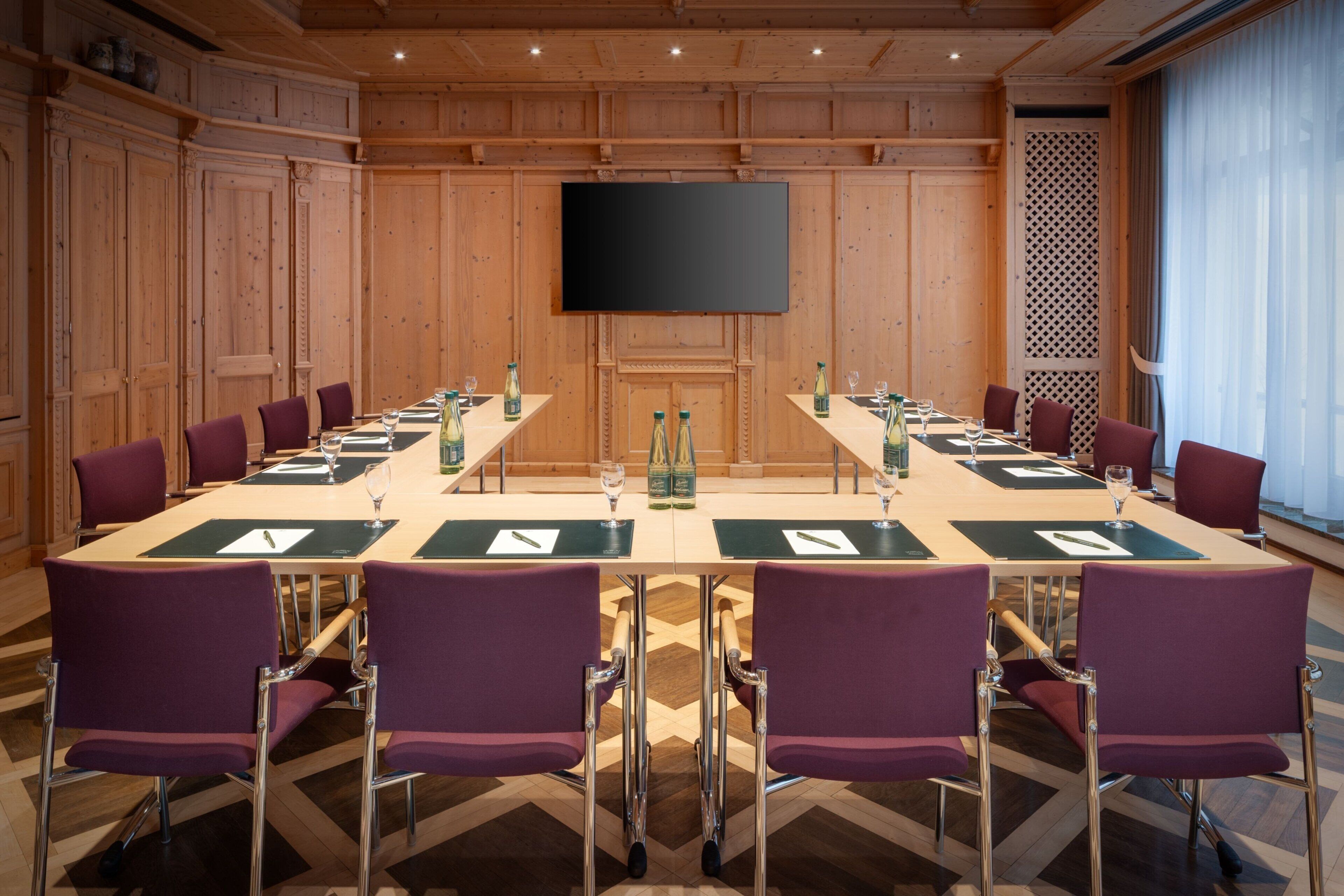 A conference room with a long table, chairs, and a flat-screen TV on the wall.