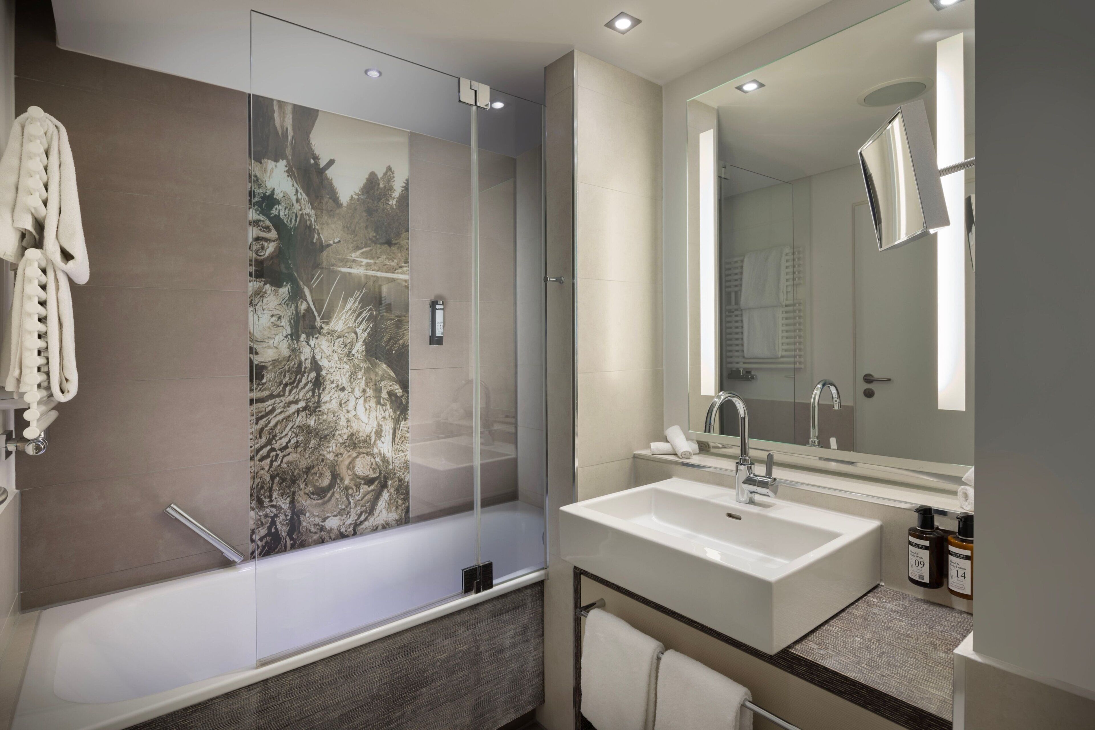 Un baño moderno con un espejo grande, una bañera y un lavamanos.