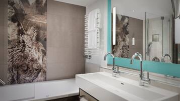 Un baño moderno con tocador doble lavamanos, un espejo grande y un perchero de toallas en la pared.