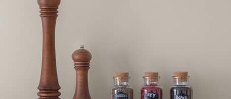 Un molinillo de madera y tres frascos de vidrio etiquetados con distintos tipos de pimienta.