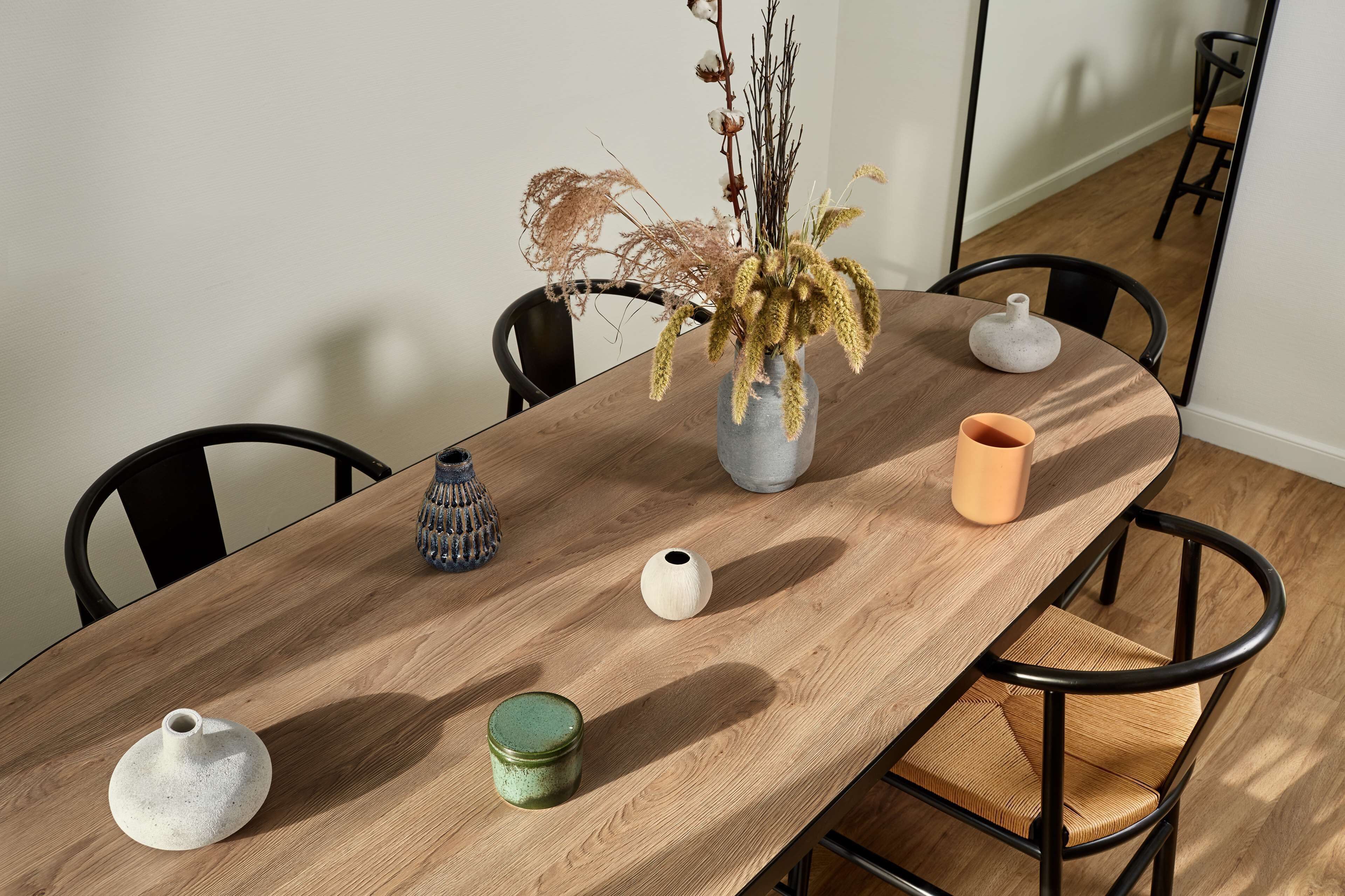 A wooden dining table with four vases and a candle.