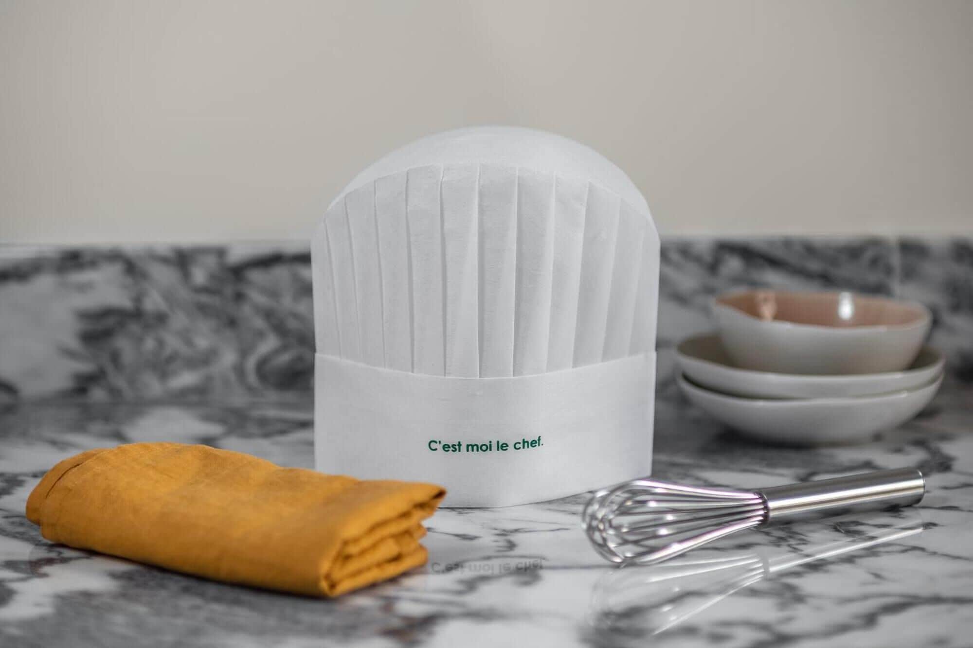 Un plan de travail de cuisine avec un appareil électroménager blanc, une serviette jaune enroulée et un fouet.