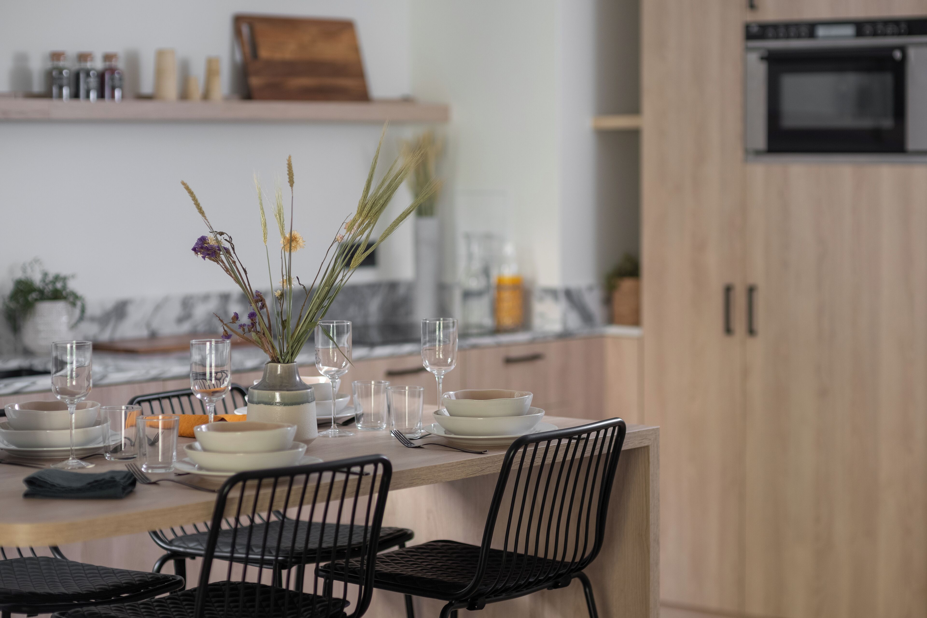 A dining table set with plates, glasses, and cutlery, with chairs around it.