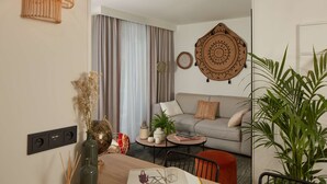 A modern living room with a sofa, coffee table, and a dining area with chairs. There are decorative items like a vase, a plant, and a wall hanging. - Pepper & Paper Apartments (Paris)