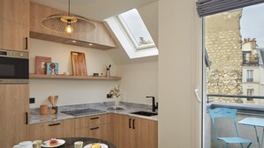 A modern kitchen with wooden cabinets, a marble countertop, and a skylight. - Pepper & Paper Apartments (Paris)