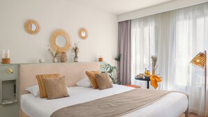 A neatly arranged hotel room with a large bed, a bedside table with a lamp, and a view of the outdoors through sheer curtains. - Pepper & Paper Apartments (Paris)