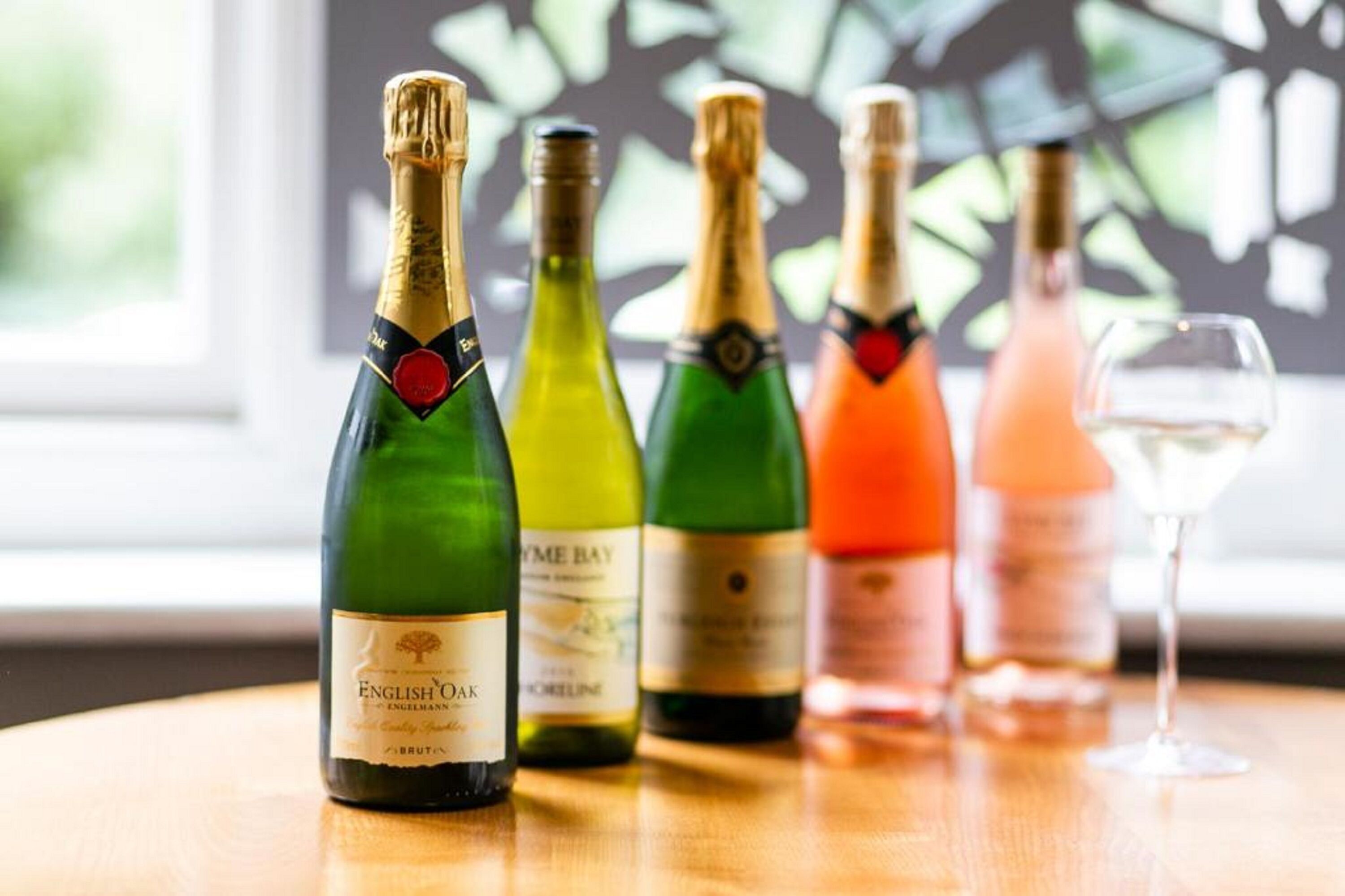 A selection of wine bottles on a wooden table with a window in the background.