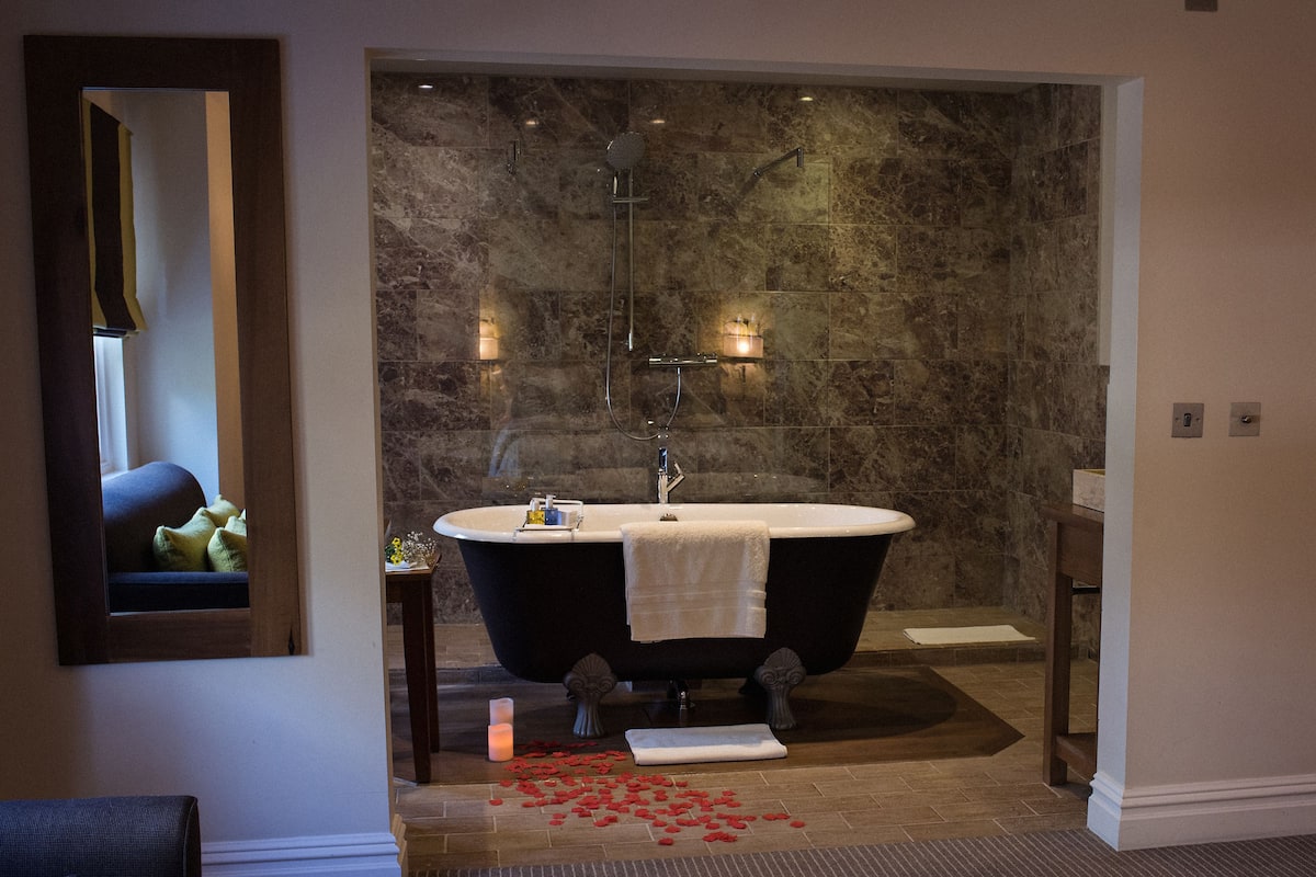A bathroom with a freestanding bathtub, a mirror, and a small table with a candle.