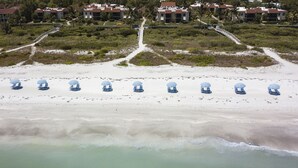 Ein Strand mit blauen und weißen Streifenmuster-Strandsonnenschirmen und Liegestühlen.