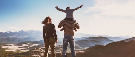 Two people on a mountain with a view of distant mountains and a valley.