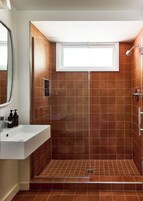 Un baño moderno con ducha, lavamanos y ventana.