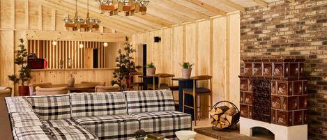 A cozy wooden interior with a sectional sofa, two round coffee tables, a fireplace, and a dining area.