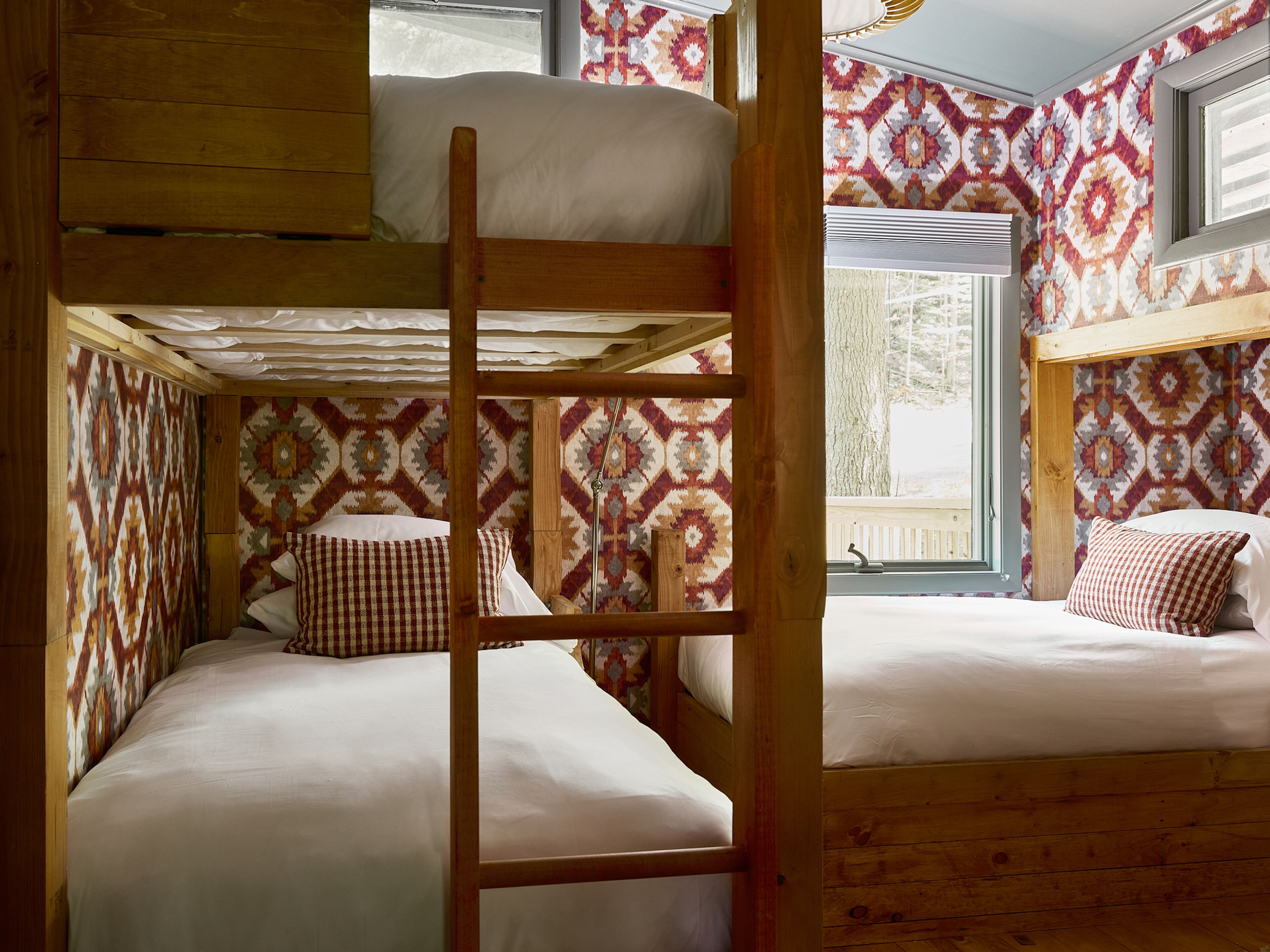 A bunk bed room with patterned wallpaper and wooden beams.