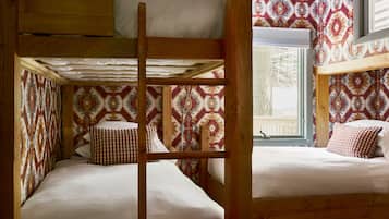 A bunk bed room with patterned wallpaper and wooden beams.