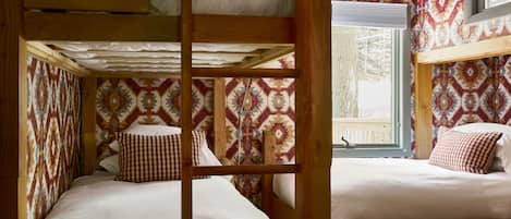 Habitación con literas, papel tapiz estampado y vigas de madera.