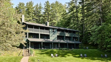 A two-story building with a balcony on the upper floor, surrounded by trees.