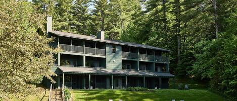 A two-story building with a balcony on the upper floor, surrounded by trees.
