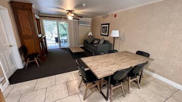 A dining area with a wooden table and chairs, a sofa, and a ceiling fan.