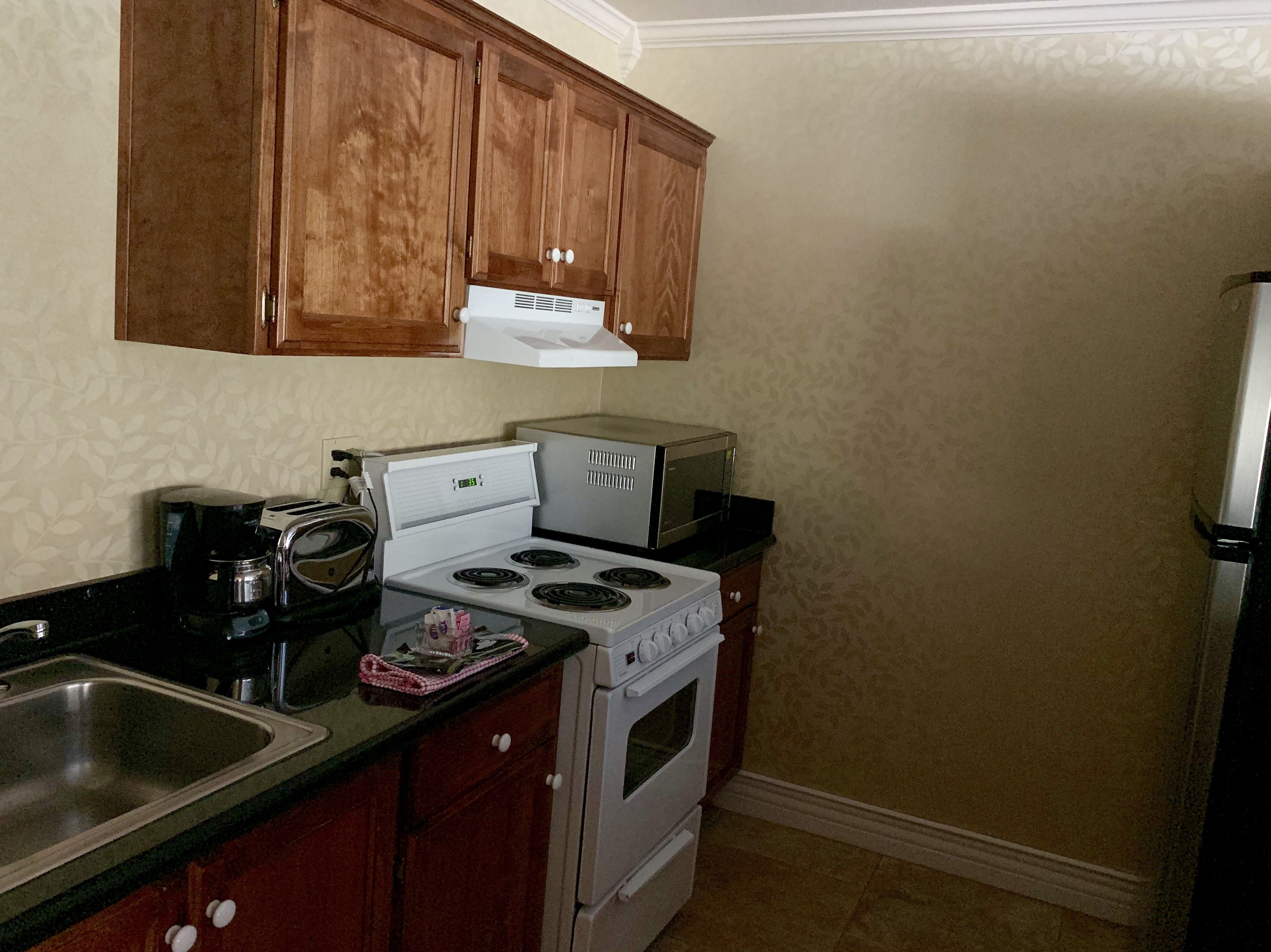 A kitchen with wooden cabinets, a stove, a microwave, and a coffee maker.