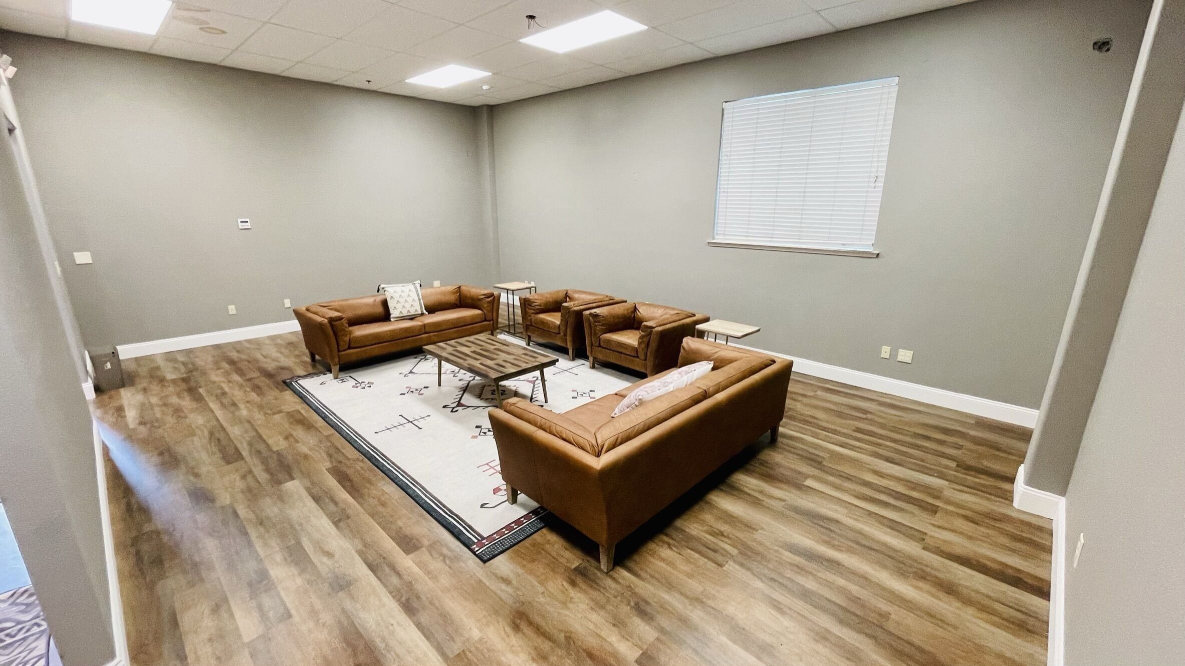 A spacious room with a large sectional sofa, a coffee table, and a patterned rug.