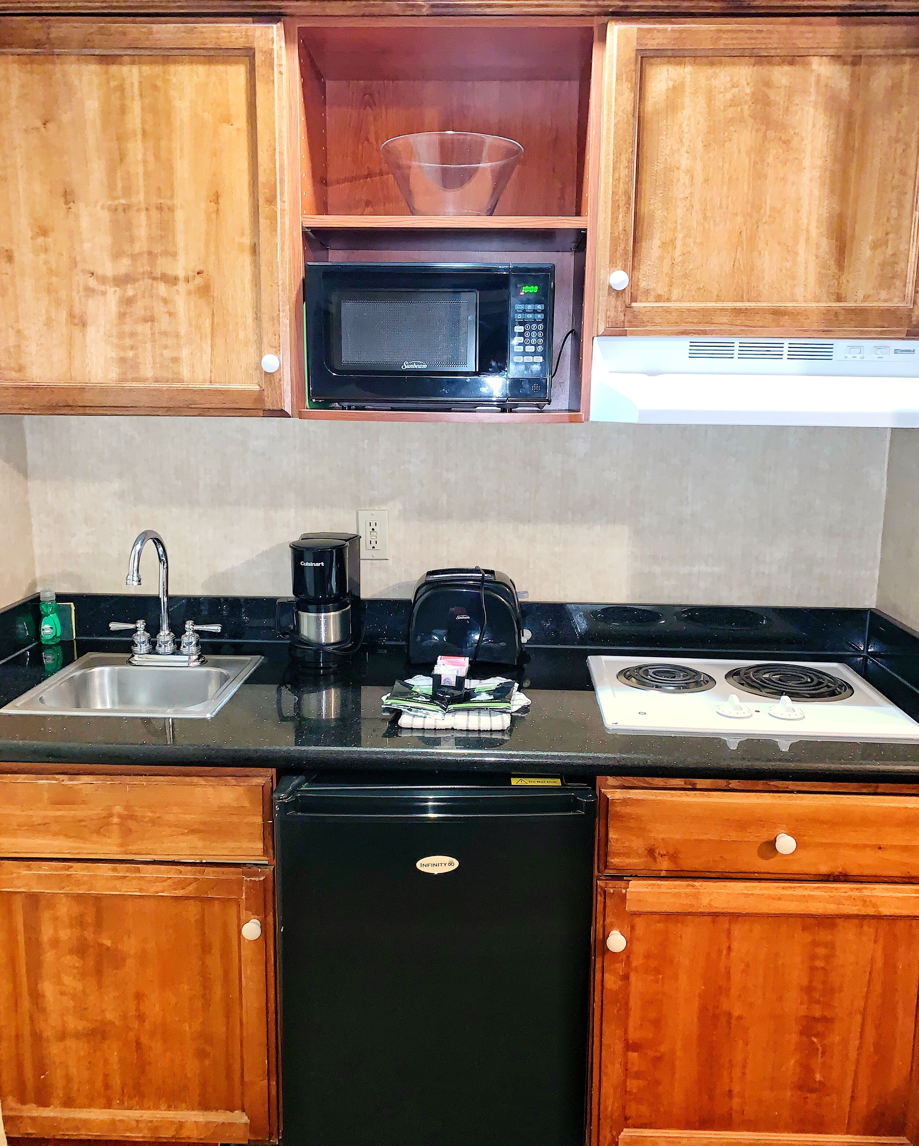 Cucina con mobili in legno, forno a microonde, lavello, macchina da caffè ed elettrodomestici.