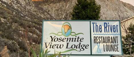 Señal de Yosemite View Lodge y The River Restaurant & Lounge, con montañas al fondo.