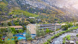 A hotel with a pool, surrounded by a rocky riverbed and mountains. - Yosemite View Lodge (El Portal)