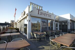 A Taverne hotel with outdoor seating and a flag.