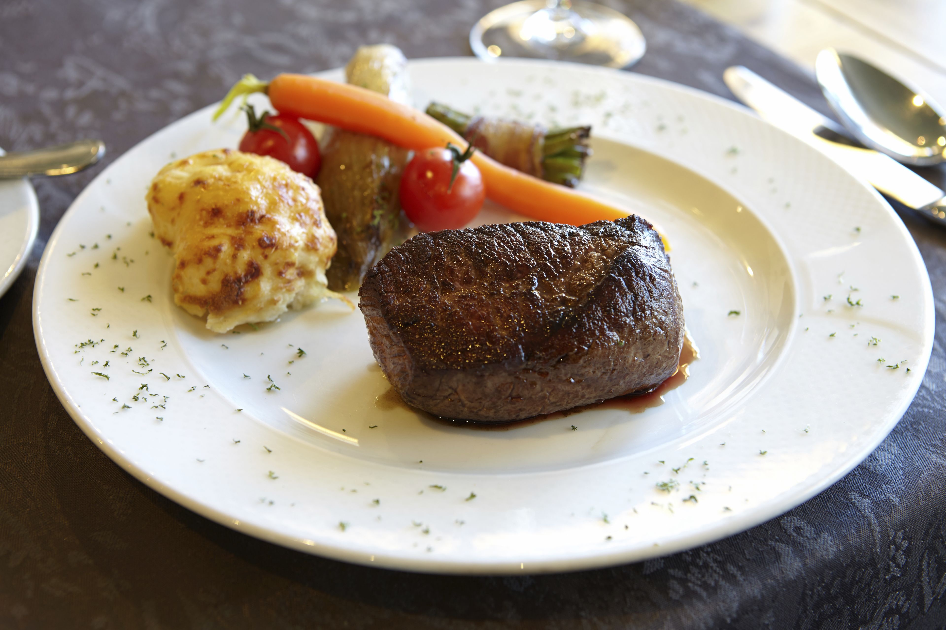 A plate with a steak, a baked potato, and vegetables.