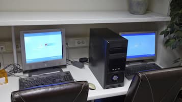 Un espace de travail équipé de deux ordinateurs de bureau, d’un clavier, d’une souris et de fauteuils en cuir.
