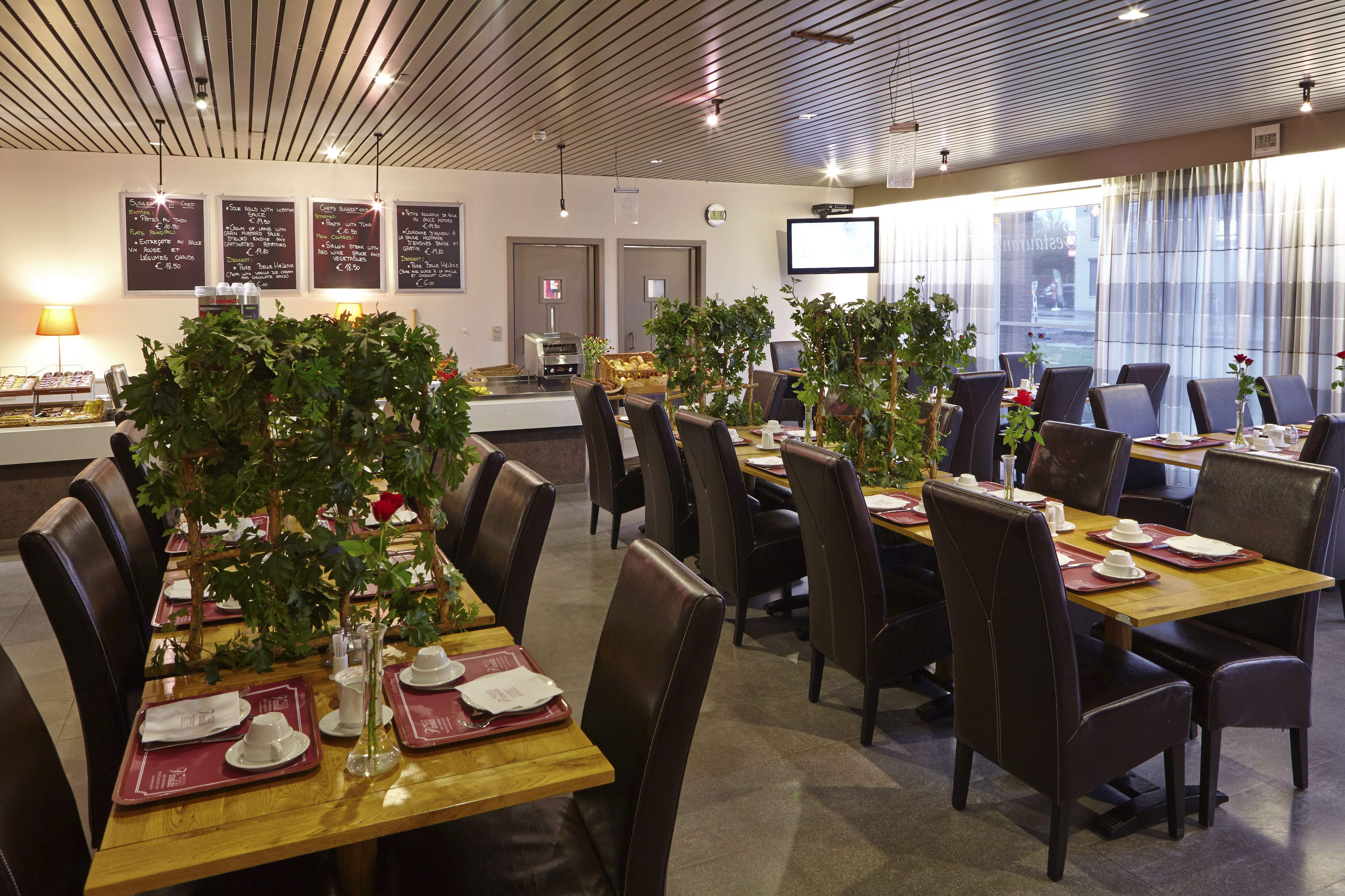 Ein Restaurant mit mehreren Tischen, Stühlen und Topfpflanzen.