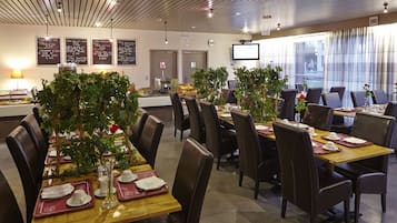Ein Restaurant mit mehreren Tischen, Stühlen und Topfpflanzen.