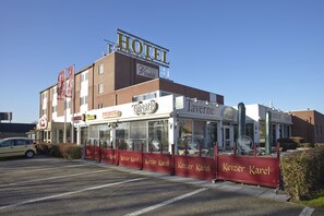 A hotel with a prominent 'HOTEL' sign, a 'Keizer Karel' restaurant, and a 'Tavern' across the street.
