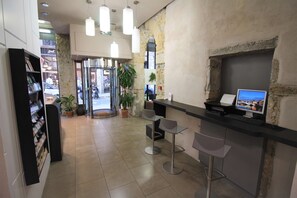 A reception area with a counter, two bar stools, a computer monitor, and a potted plant. - Best Western Hotel Saint Antoine (Lyon)