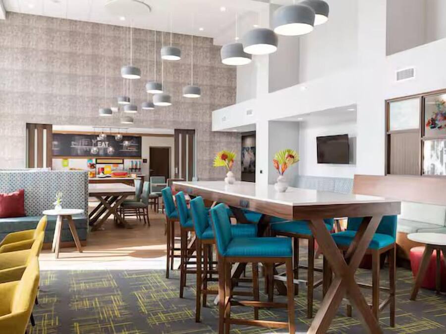 Un interior moderno con una zona de bar, asientos y una cocina al fondo.