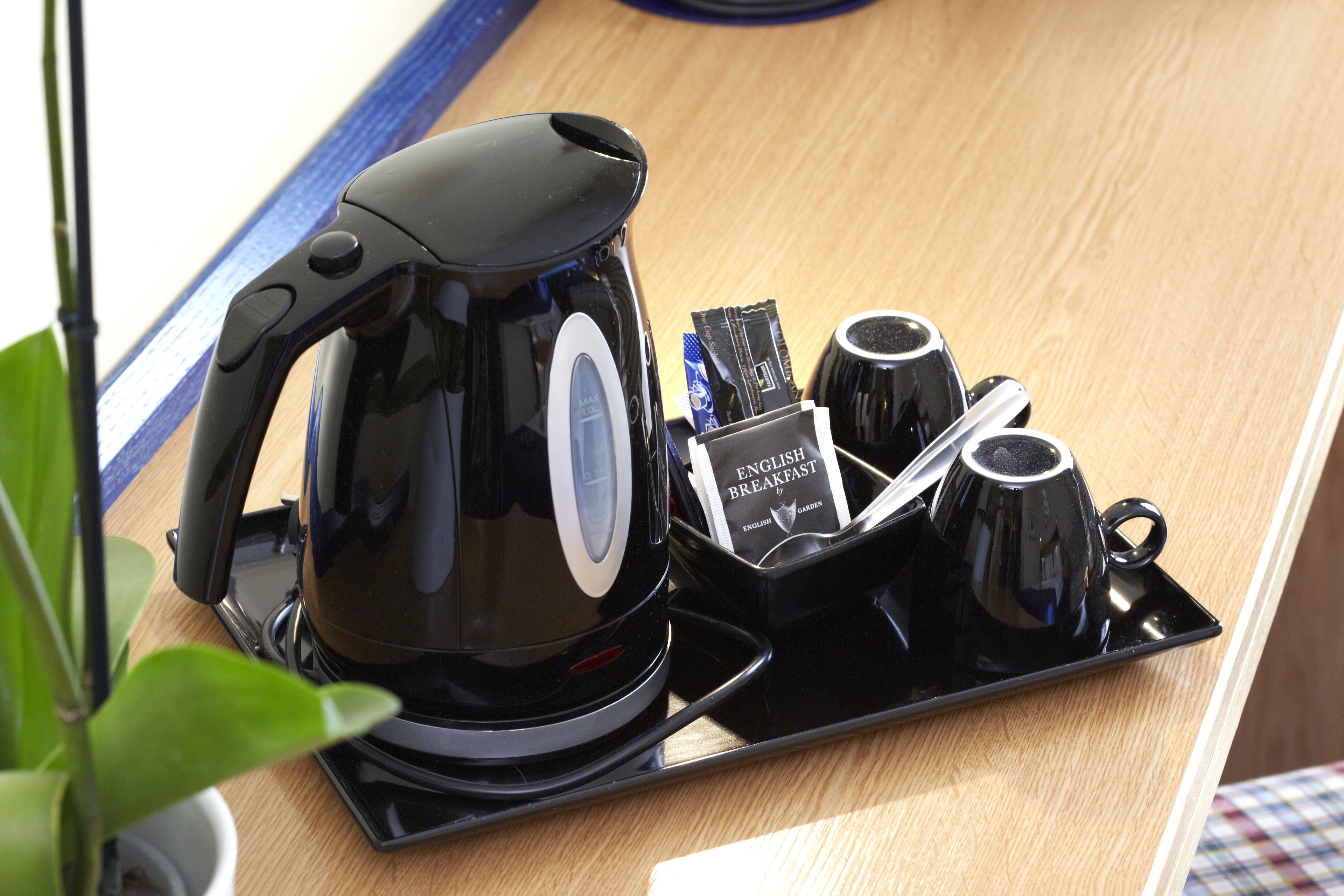 Una cafetera con una bandeja, dos tazas y un libro titulado 'English Breakfast' sobre una mesa de madera.