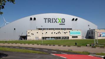 Um edifício grande e moderno com o nome 'TRIXXO ARENA' em destaque.
