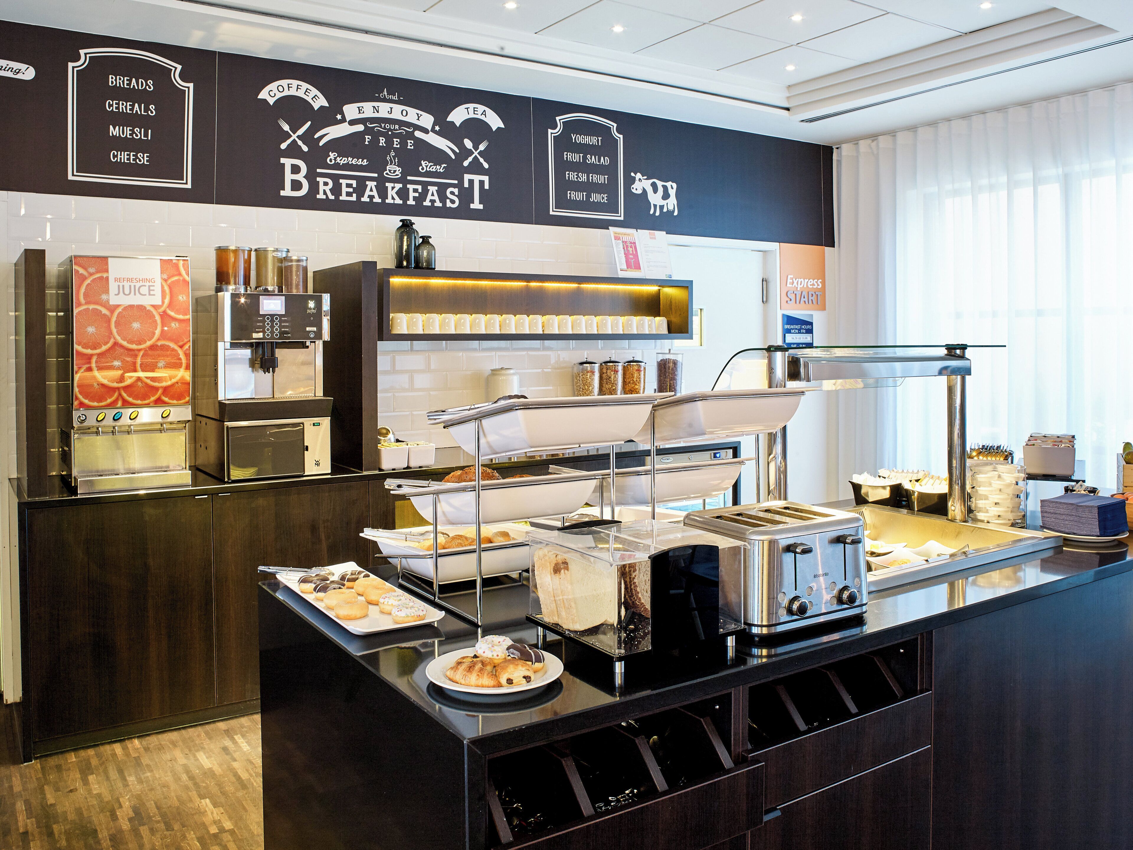 Un espace buffet pour le petit-déjeuner comprenant un coin café, un distributeur de jus et une variété d’aliments.
