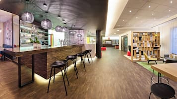 A modern bar area with stools, a bar counter, and a variety of bottles.