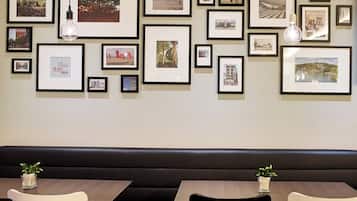 Un mur orné de plusieurs photographies encadrées et éclairé par deux lampes suspendues.