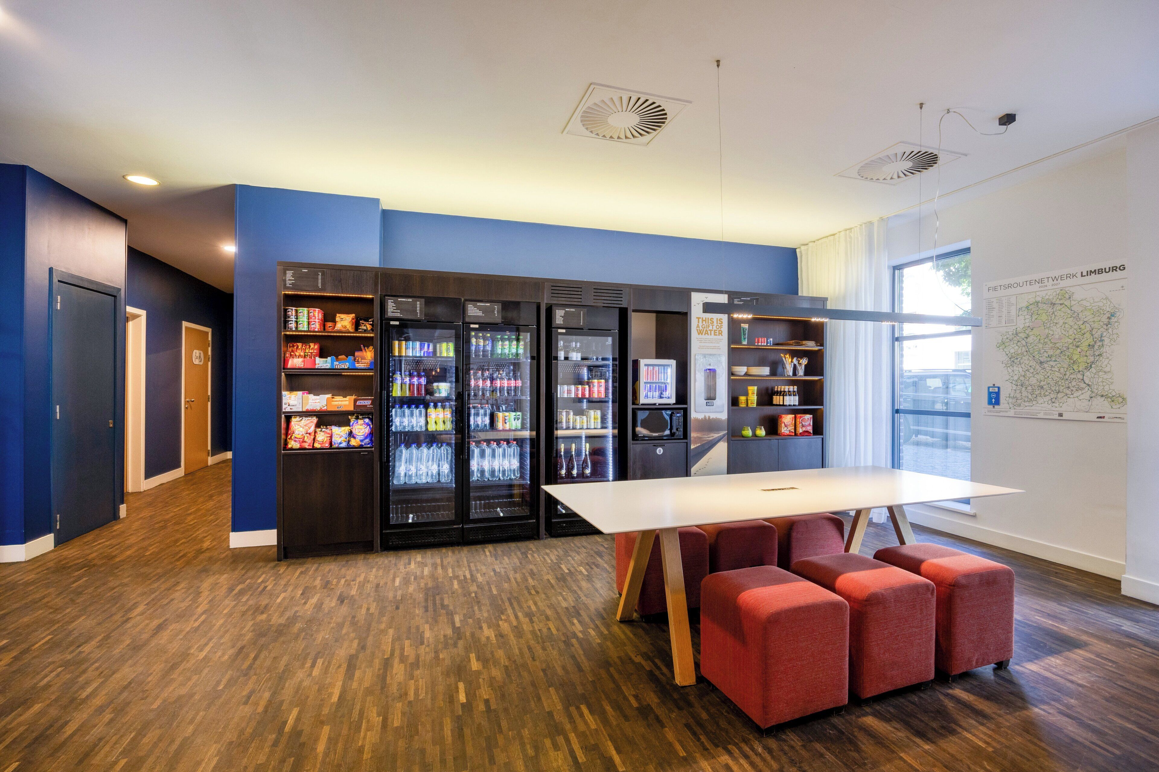 A modern interior with a white table and red seating, a wall-mounted map, and vending machines.