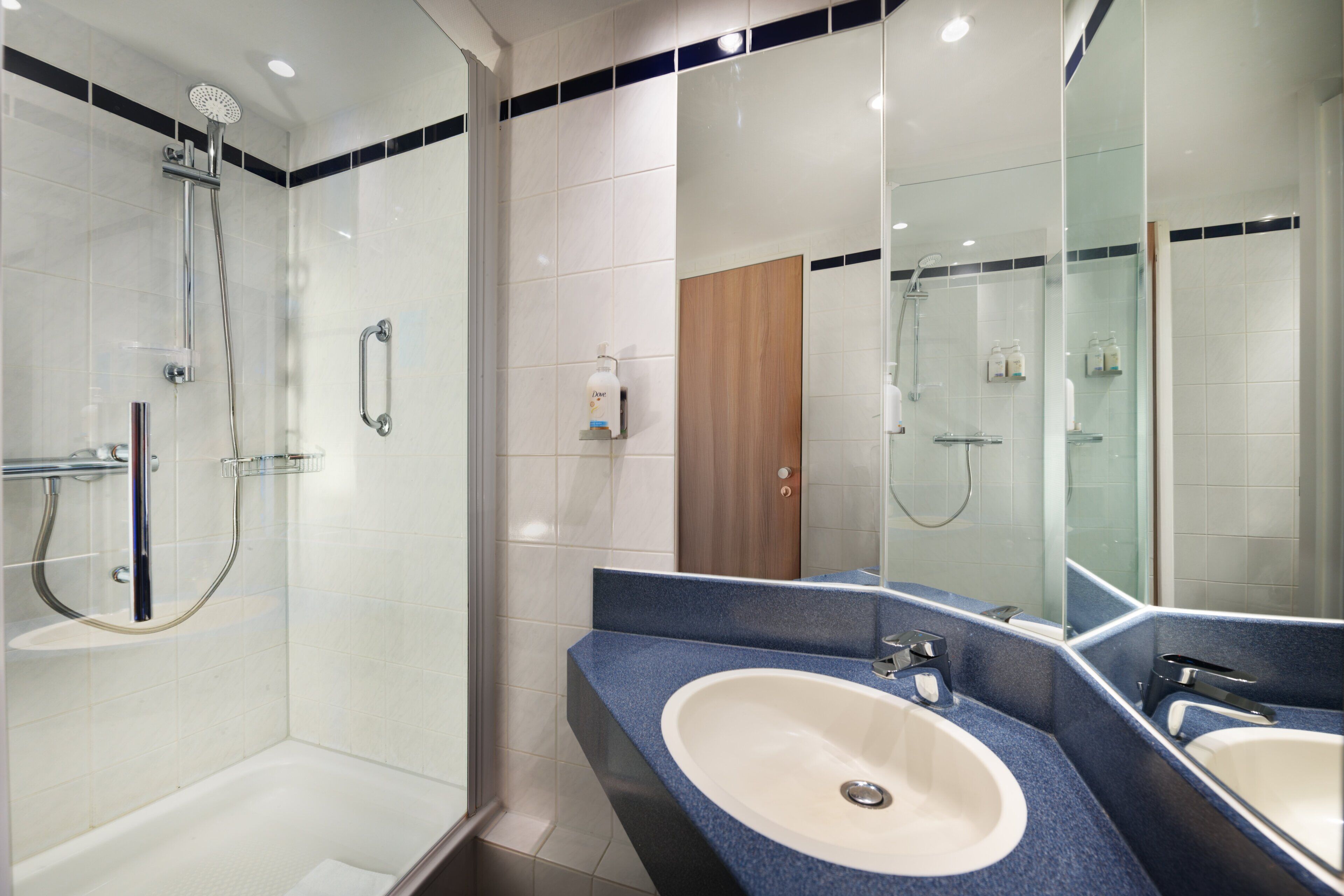 A modern bathroom with a glass shower enclosure, a double sink vanity, and a large mirror.