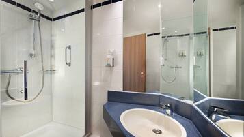 A modern bathroom with a glass shower enclosure, a double sink vanity, and a large mirror.