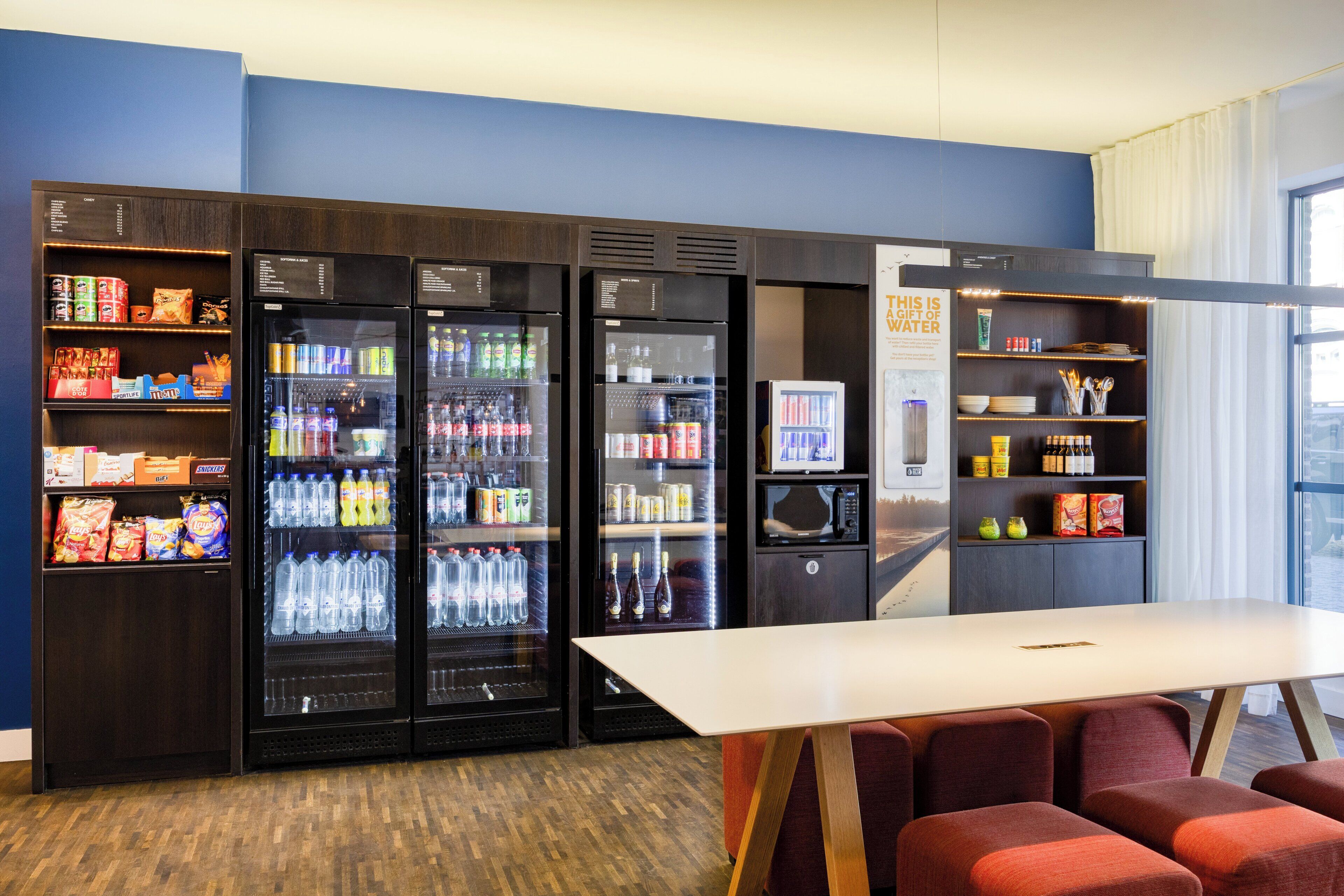 Habitación de hotel con minibar, zona de estar y vistas a la ciudad.