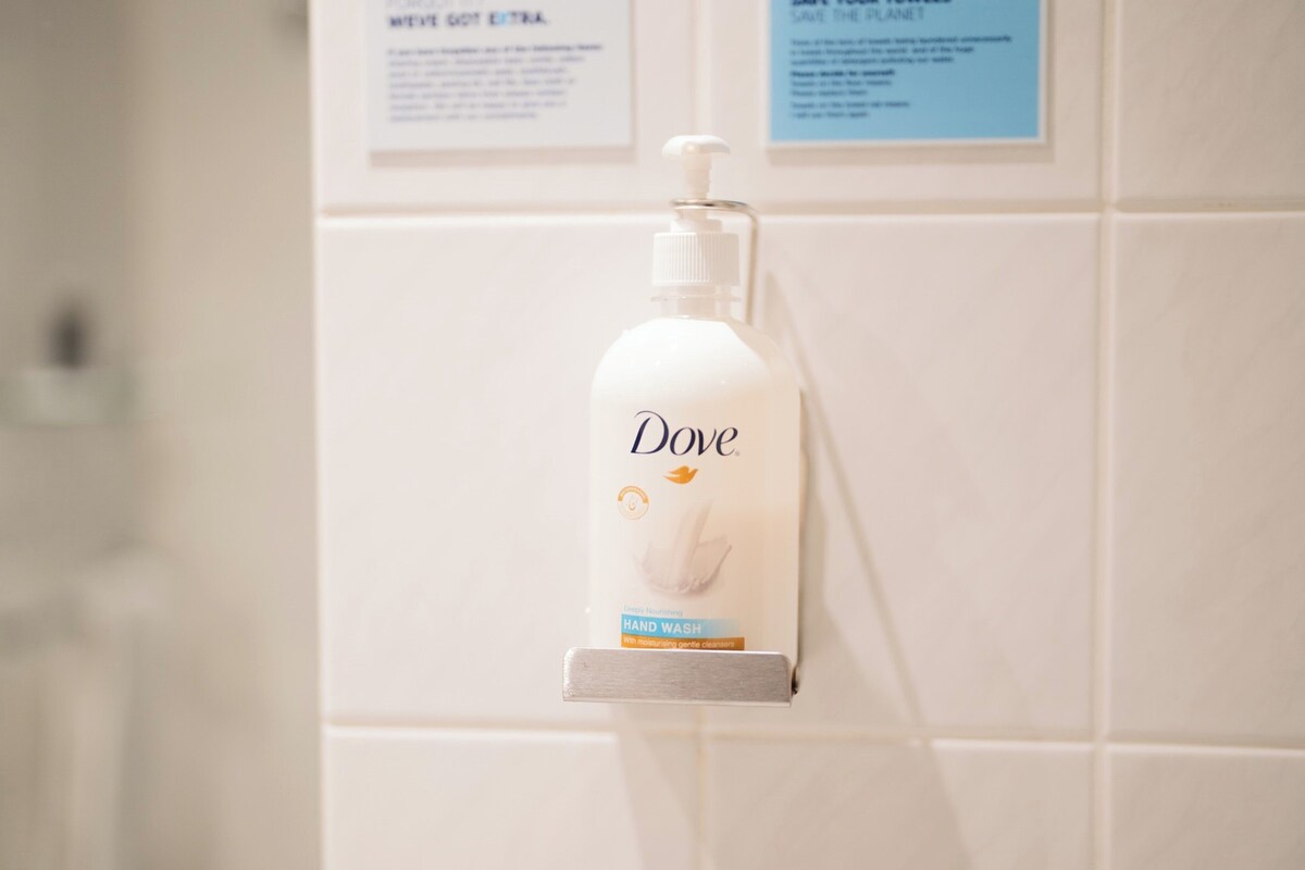Un distributeur de savon liquide Dove fixé sur un mur recouvert de carreaux.