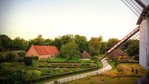 A traditional windmill with a thatched roof, surrounded by a well-maintained garden with neatly trimmed hedges and a variety of plants. - Holiday Inn Express Hasselt by IHG (Hasselt)