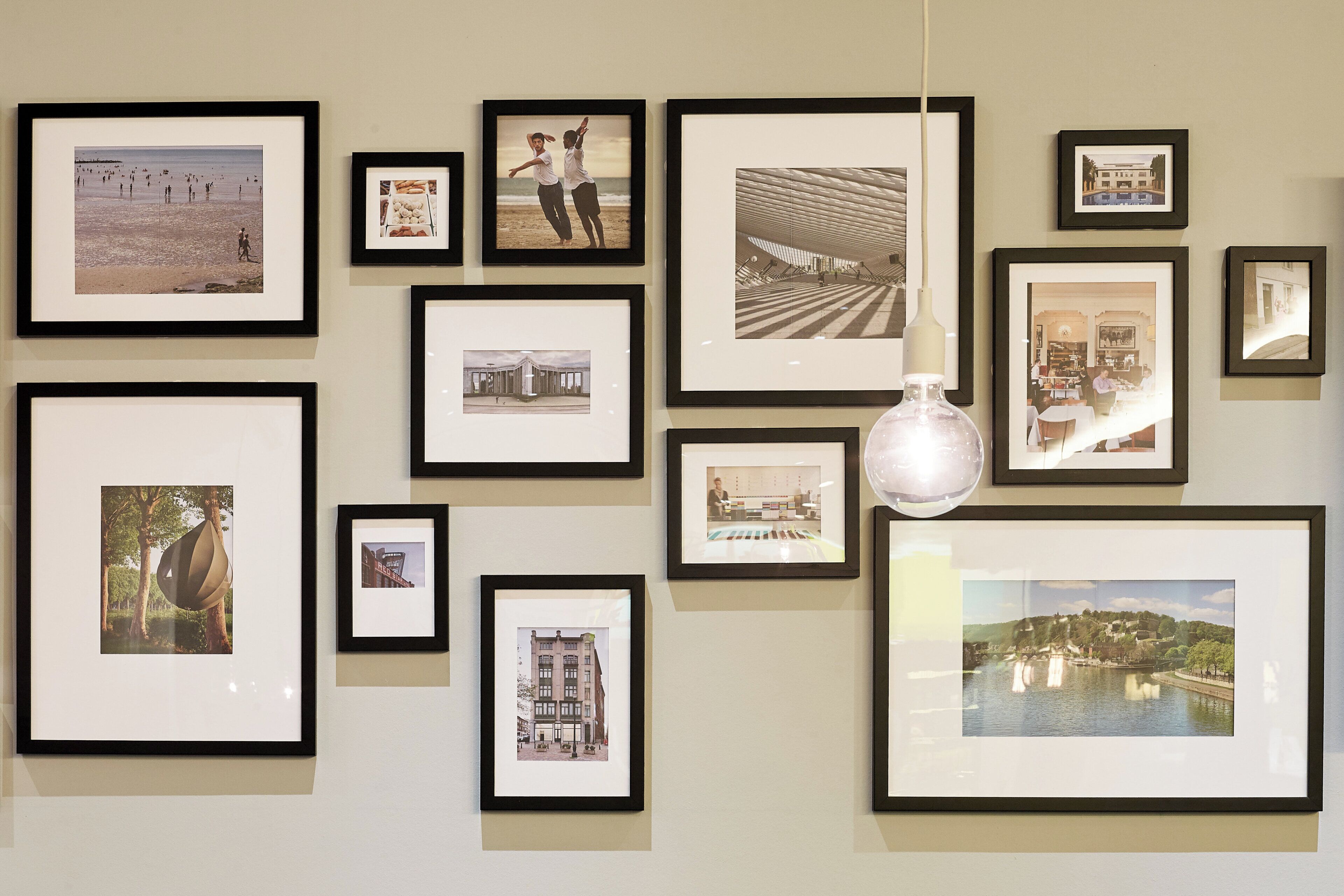 A wall with multiple framed photographs of various locations and architectural structures.