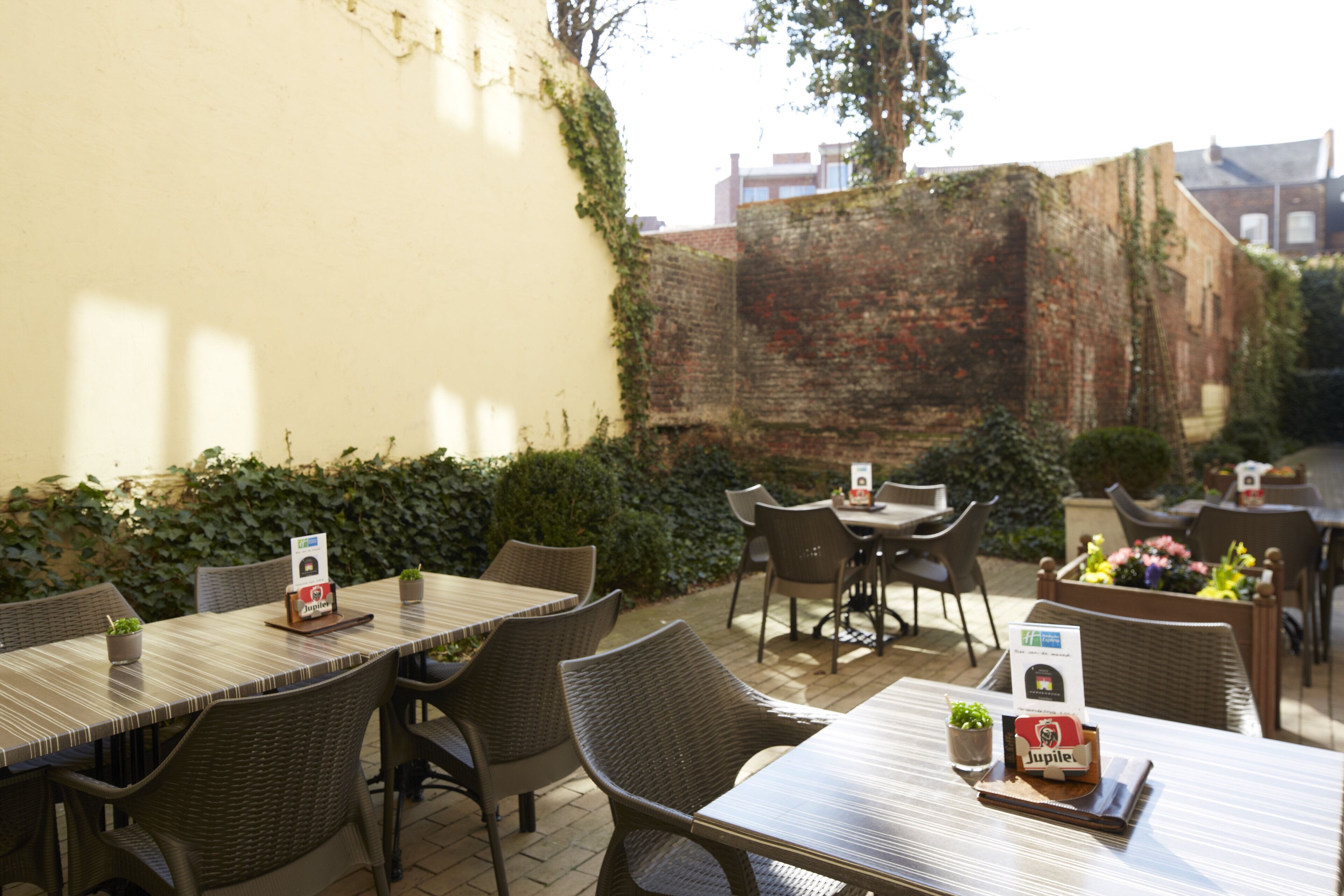 Ein Terrassenbereich im Freien mit Tischen und Stühlen, einige davon mit Speisekarten und einem Jupiter Bieruntersetzer.