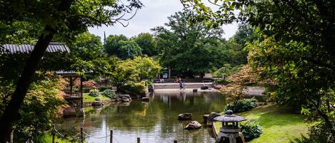 A serene garden with a pond, stone lantern, and traditional Japanese architecture.